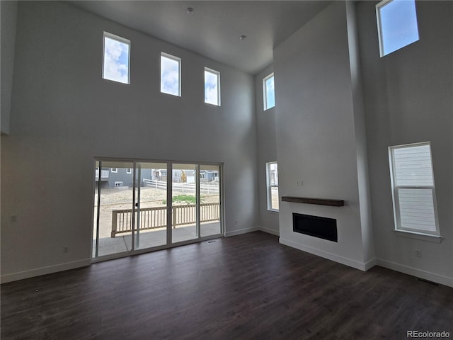 5629 Farrier Pt, Castle Rock, CO 80104 - unfurnished living room with a towering ceiling, dark wood-style floors, a fireplace, and baseboards