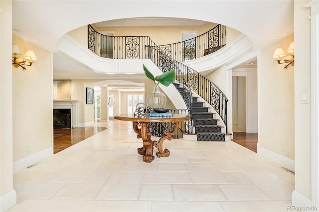 foyer entrance featuring crown molding, a towering ceiling, and decorative columns