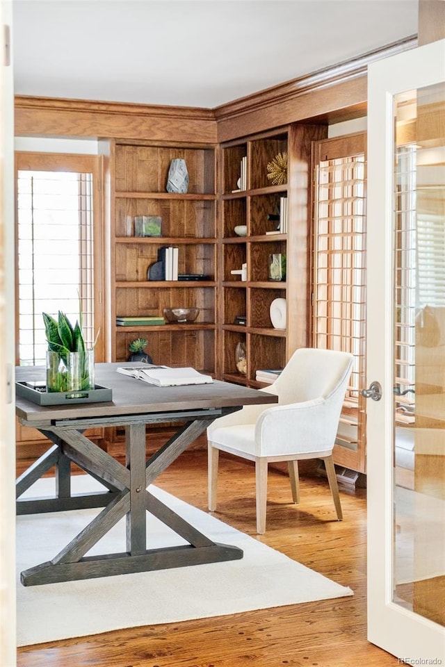 living area with wood-type flooring, built in features, and french doors