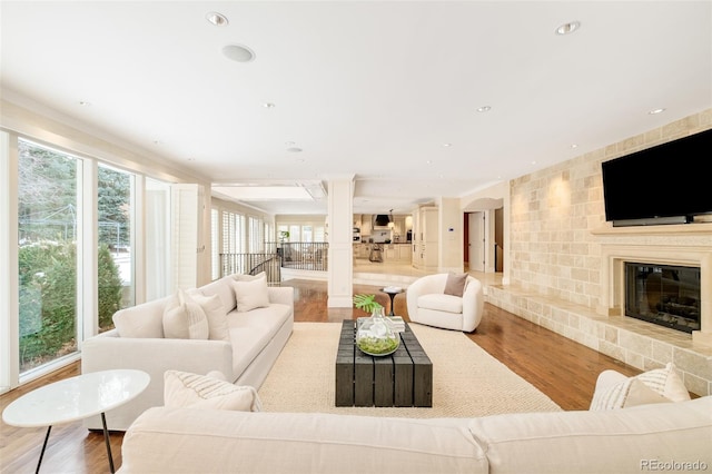 living room featuring ornamental molding, a large fireplace, and hardwood / wood-style floors