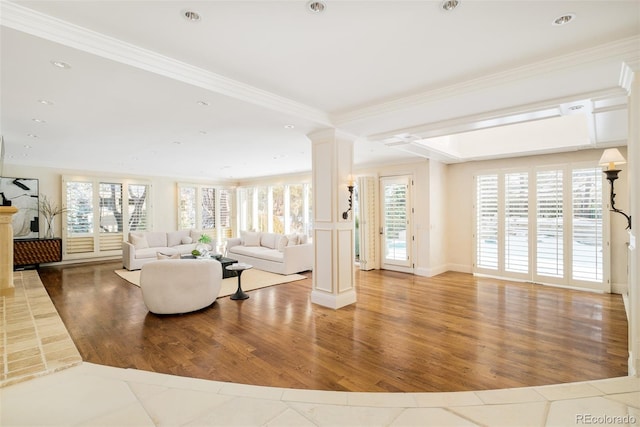 living room featuring hardwood / wood-style floors, crown molding, and ornate columns