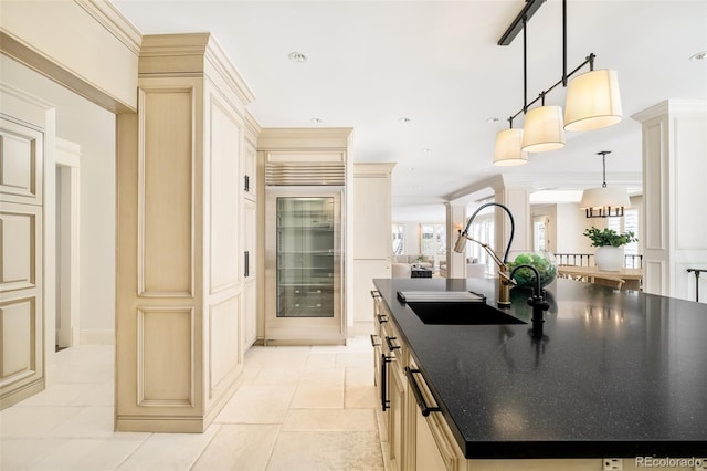 kitchen featuring sink, decorative light fixtures, cream cabinets, and beverage cooler