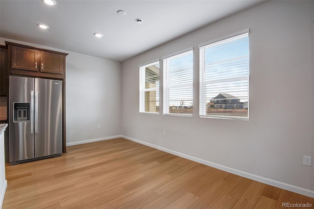 kitchen with dark brown cabinetry, light wood-type flooring, and stainless steel fridge with ice dispenser