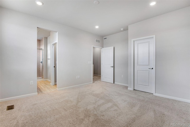 unfurnished bedroom with ensuite bath and light colored carpet