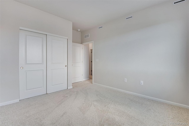 unfurnished bedroom featuring light colored carpet and a closet