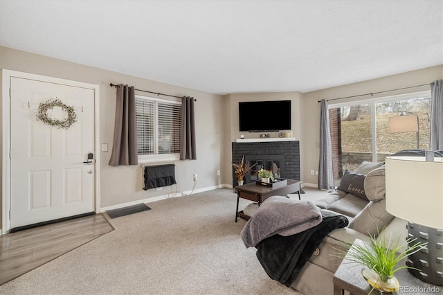 living area with a brick fireplace, heating unit, carpet, and baseboards