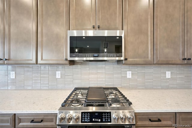 kitchen featuring light stone countertops, appliances with stainless steel finishes, and backsplash