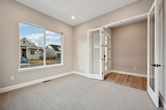 spare room with light carpet, french doors, visible vents, and baseboards