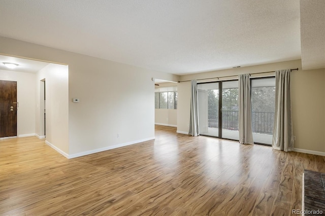 unfurnished room featuring light hardwood / wood-style flooring and a textured ceiling