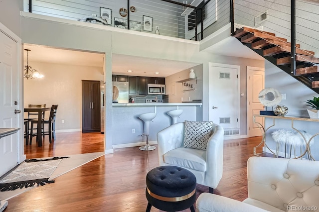 living room featuring hardwood / wood-style floors, a towering ceiling, and a chandelier