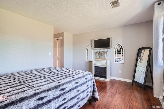 bedroom featuring a textured ceiling, a closet, and dark hardwood / wood-style floors