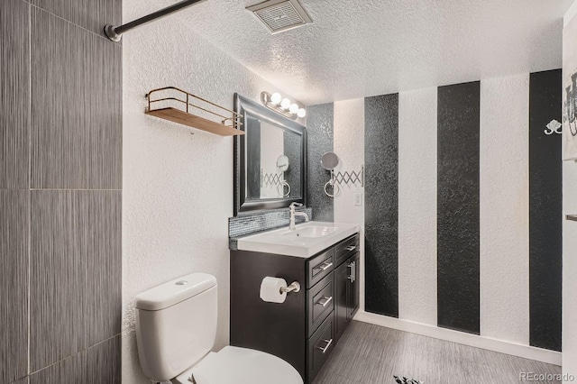 bathroom with a textured ceiling, vanity, and toilet