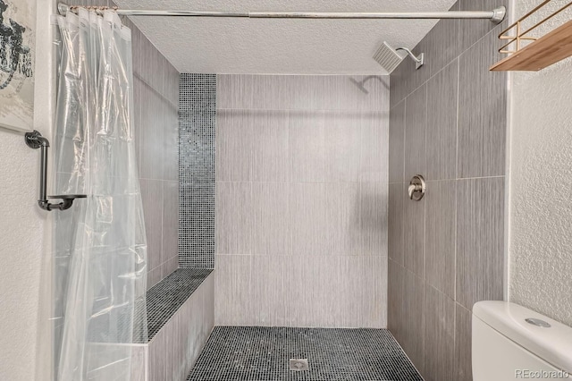 bathroom with a textured ceiling, walk in shower, and toilet