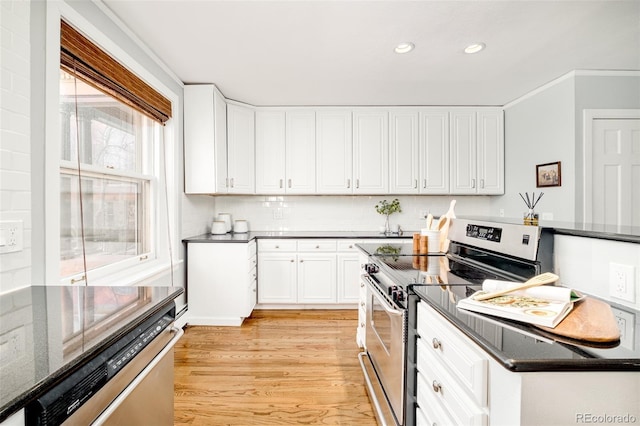 kitchen with electric stove, stove, white cabinetry, light wood-type flooring, and dark stone counters