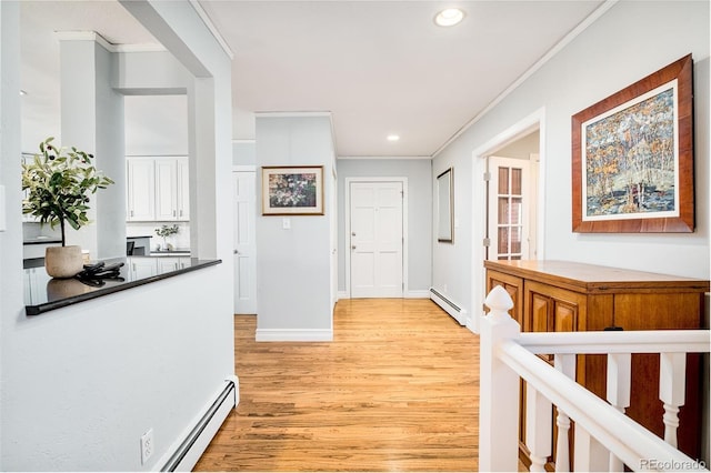 corridor with baseboard heating, crown molding, and light hardwood / wood-style flooring