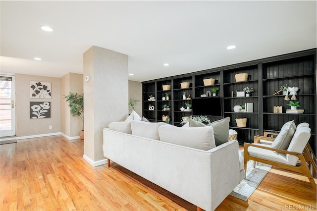 living room featuring built in shelves and light hardwood / wood-style flooring