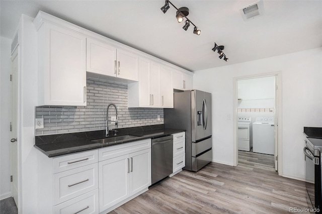 kitchen with backsplash, visible vents, a sink, separate washer and dryer, and stainless steel appliances