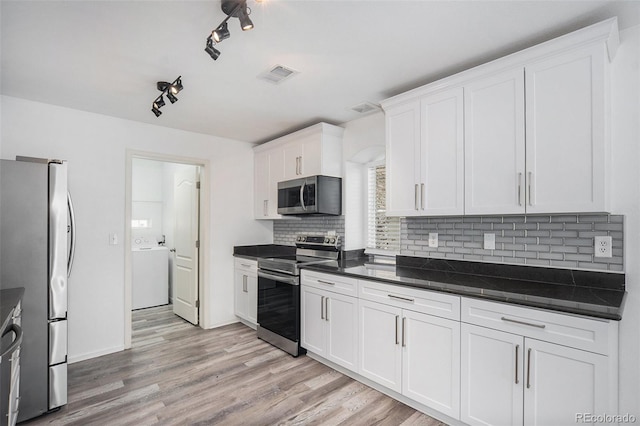 kitchen featuring visible vents, decorative backsplash, dark countertops, washer / clothes dryer, and appliances with stainless steel finishes