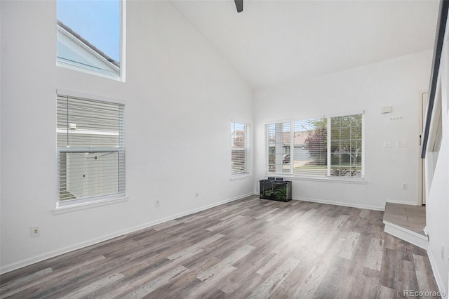 unfurnished room with baseboards, high vaulted ceiling, and wood finished floors