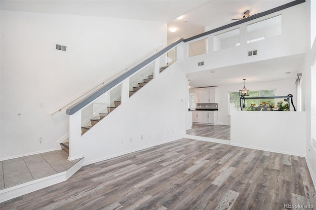 unfurnished living room featuring visible vents, wood finished floors, and stairway