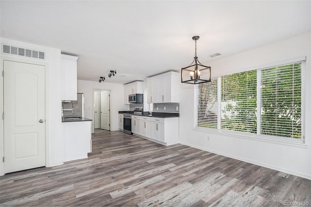kitchen featuring stainless steel appliances, a notable chandelier, visible vents, and dark countertops