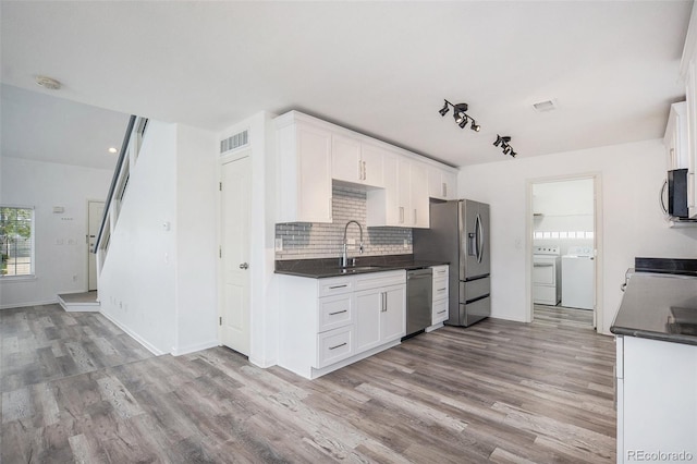 kitchen with washing machine and clothes dryer, dark countertops, appliances with stainless steel finishes, and visible vents