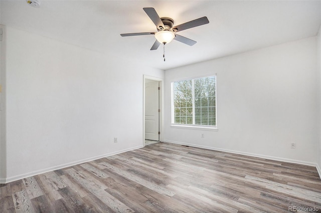 spare room with baseboards, ceiling fan, and wood finished floors
