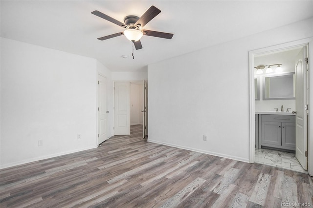 unfurnished bedroom with baseboards, wood finished floors, and ensuite bathroom