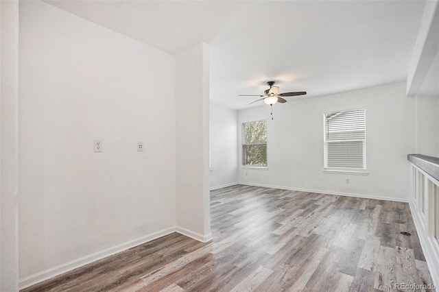 unfurnished room with baseboards, a ceiling fan, and wood finished floors