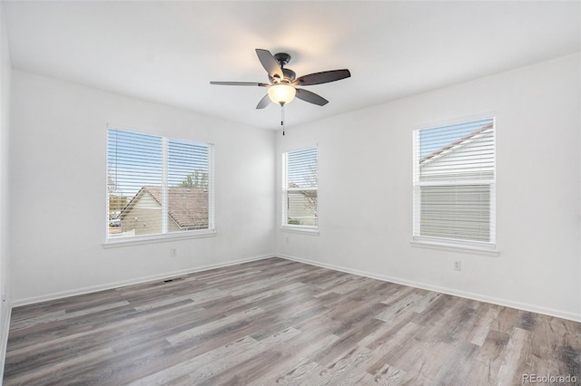 empty room featuring baseboards, ceiling fan, and wood finished floors