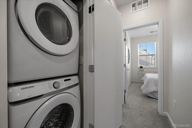 washroom featuring stacked washer / drying machine and light carpet