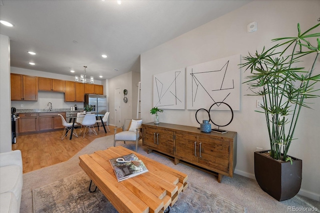 living area featuring recessed lighting, baseboards, light wood-style floors, and a chandelier