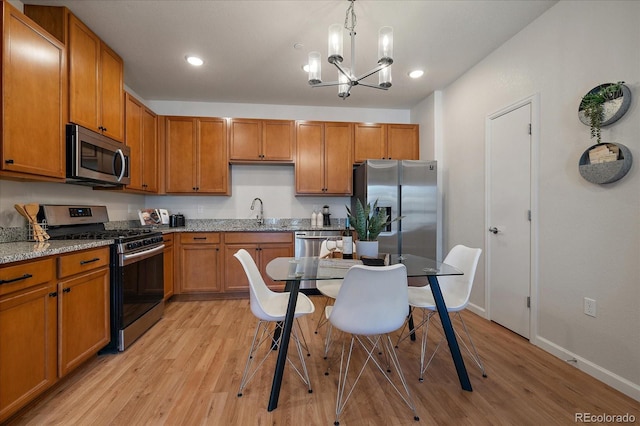 1841 S Dunkirk St Unit 203, Aurora, CO 80017 - kitchen featuring appliances with stainless steel finishes, a chandelier, light wood-style floors, brown cabinets, and recessed lighting