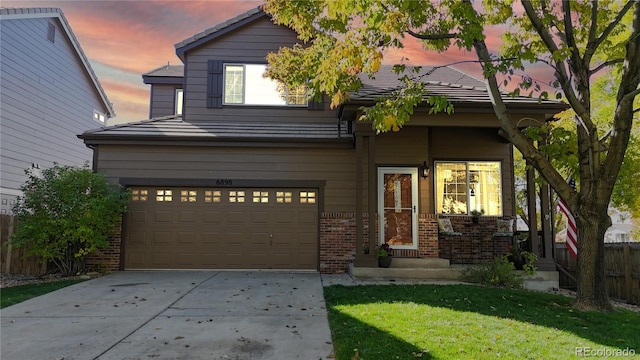 view of front of home featuring brick siding, a yard, fence, a garage, and driveway