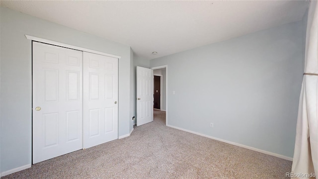 unfurnished bedroom featuring carpet floors, baseboards, and a closet