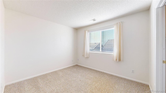 spare room with baseboards, visible vents, a textured ceiling, and carpet flooring