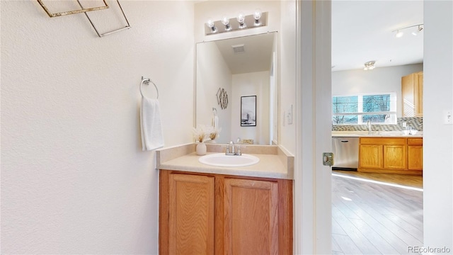 bathroom with visible vents, wood finished floors, backsplash, and vanity