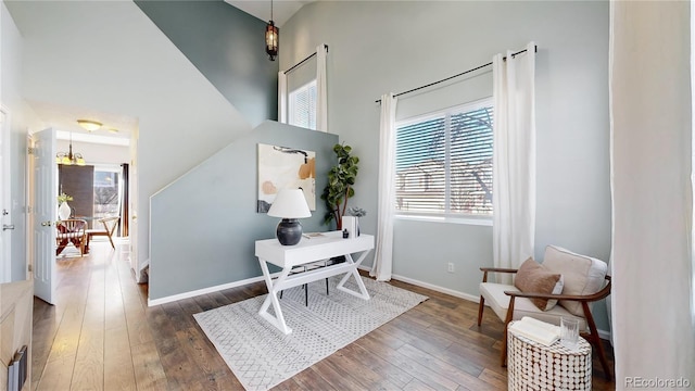 office area with a high ceiling, baseboards, and hardwood / wood-style floors