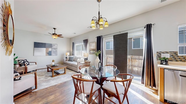 dining room featuring ceiling fan with notable chandelier, visible vents, baseboards, and wood finished floors