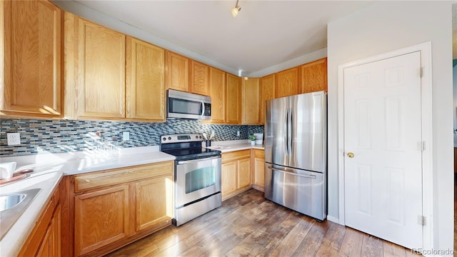 kitchen featuring light countertops, appliances with stainless steel finishes, backsplash, and wood finished floors