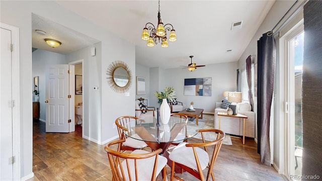 dining area with light wood-type flooring, visible vents, baseboards, and ceiling fan with notable chandelier