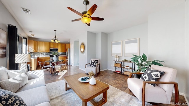 living room with light wood-type flooring, baseboards, visible vents, and ceiling fan