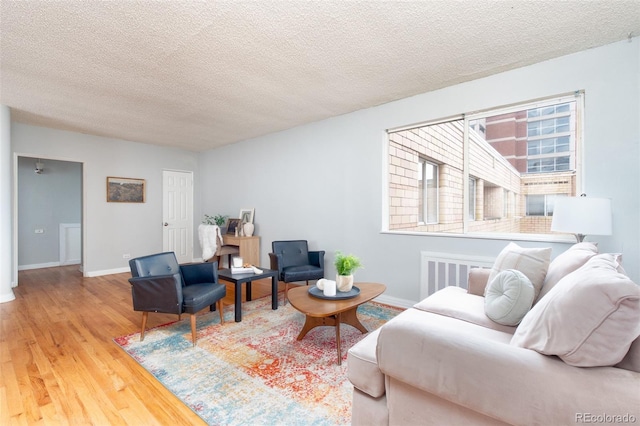 living area with baseboards, a textured ceiling, and wood finished floors