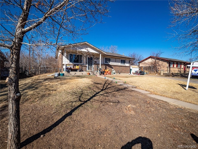 single story home with a porch, a front yard, fence, and brick siding