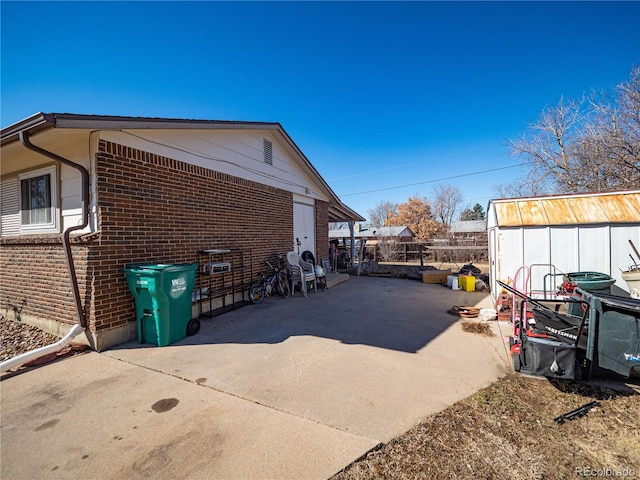 view of property exterior with brick siding and a patio