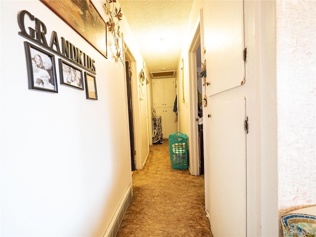 hall featuring a textured ceiling, carpet flooring, and baseboards