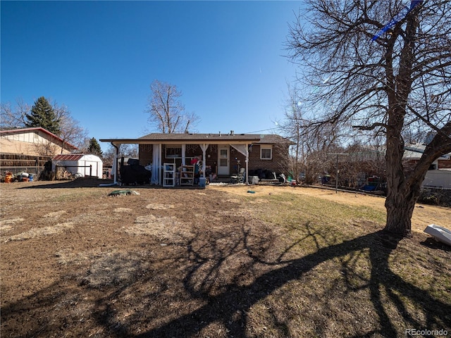 rear view of property featuring an outbuilding, a storage shed, fence, and brick siding