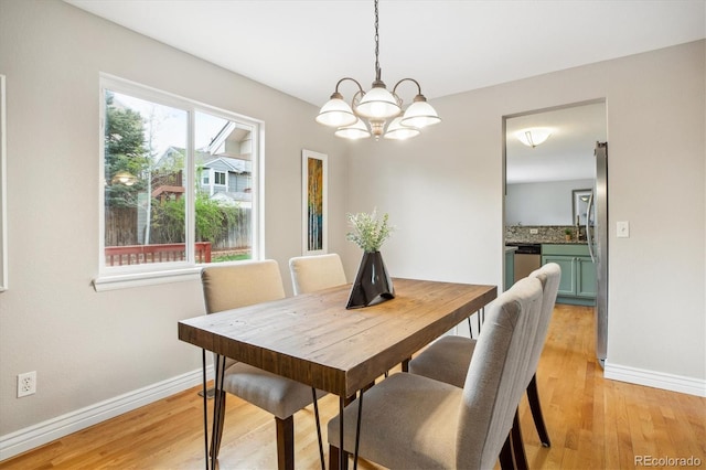 dining room featuring baseboards, light wood-type flooring, and a notable chandelier