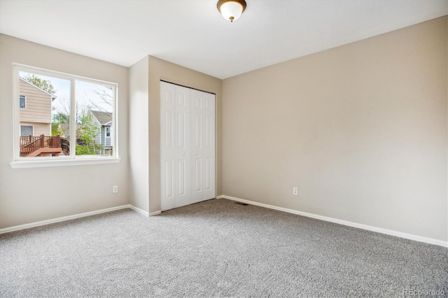 unfurnished bedroom with baseboards, carpet, and a closet