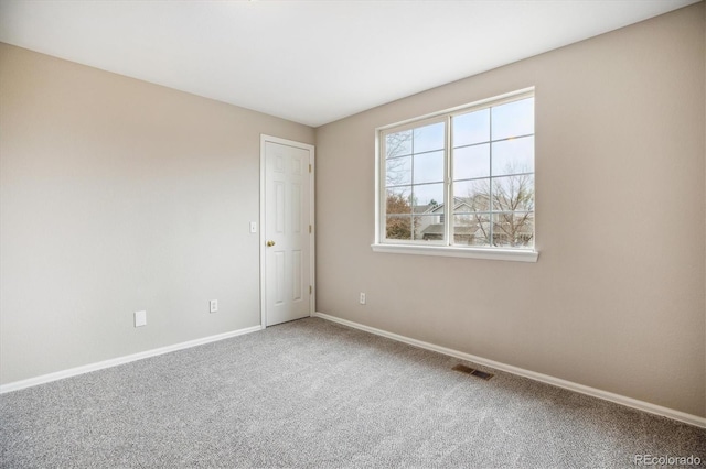 carpeted spare room featuring baseboards and visible vents